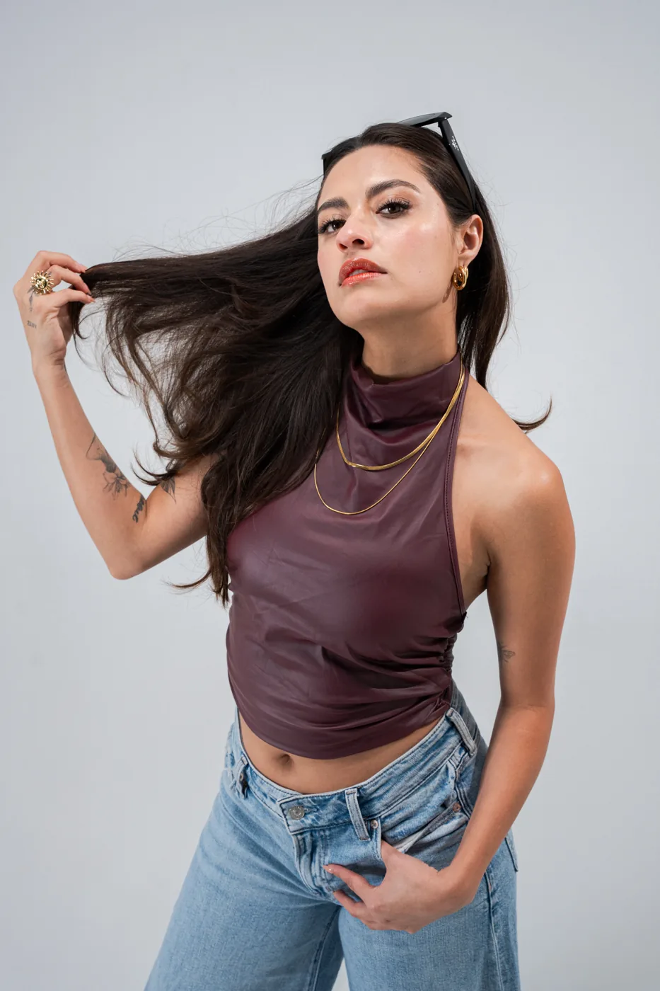 Leather halter top and flared jeans, hand in hair
