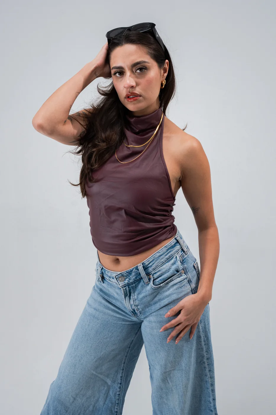 Leather halter top and flared jeans, hand on hip