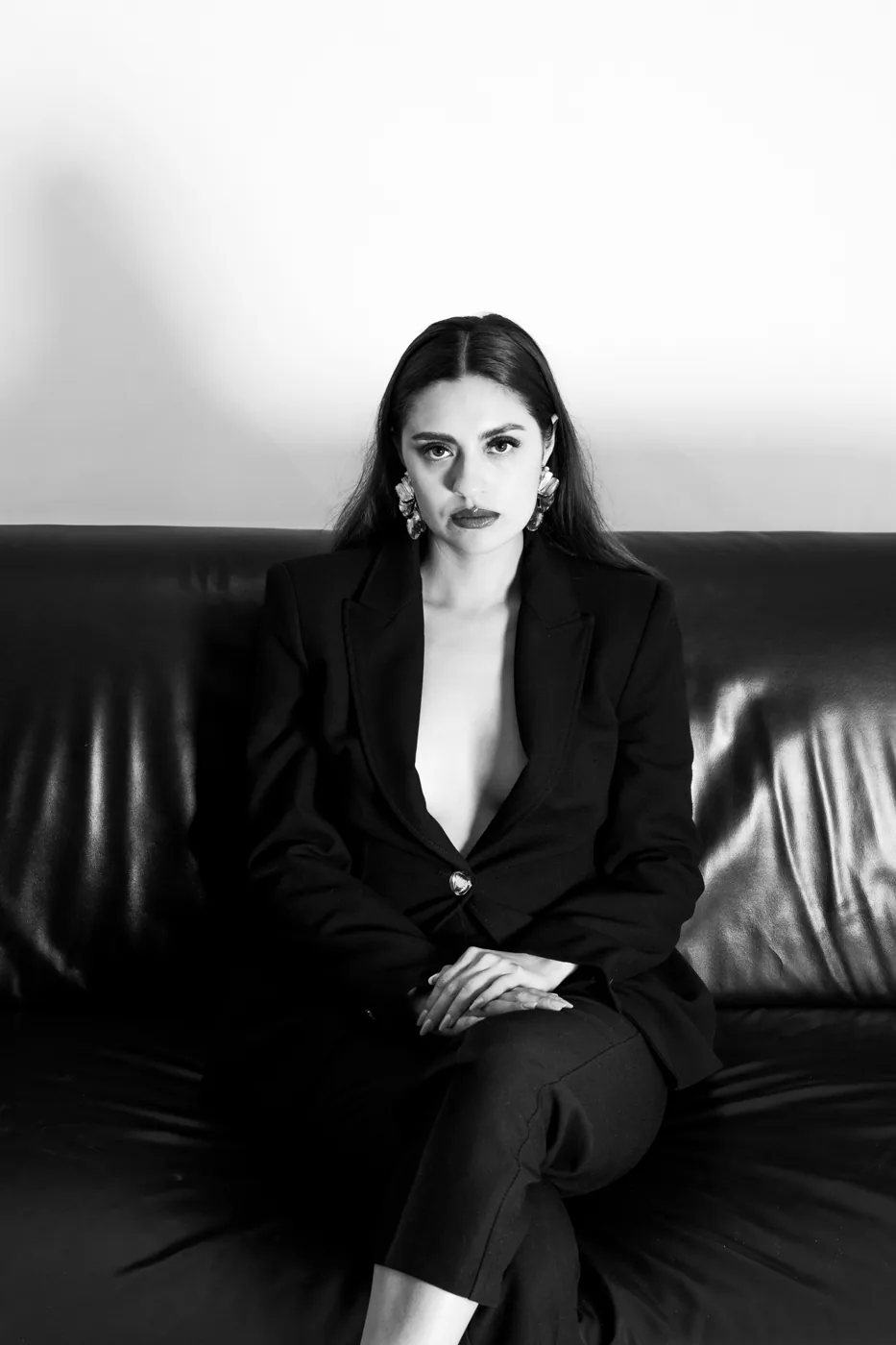 Black and white, seated in a suit on a leather sofa